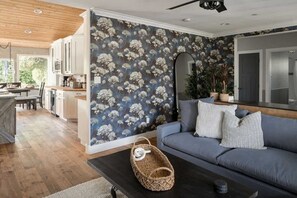 A modern living room with a grey sofa, a woven basket, and a wooden ceiling.