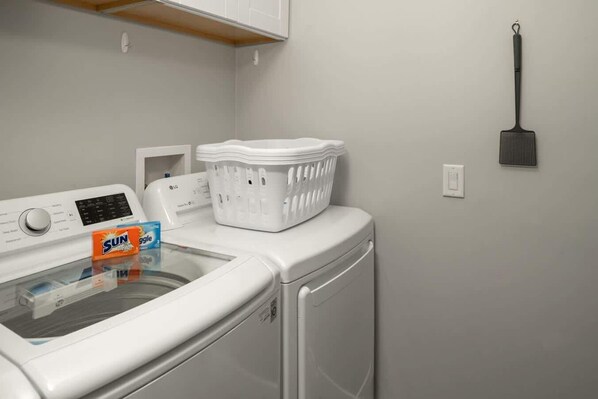 A laundry area with a washing machine, dryer, and a basket on the dryer.
