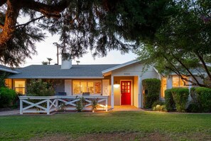 A two-story house with a red door, a covered porch, and a well-maintained lawn.