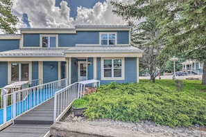 A two-story building with a blue exterior, a covered deck, and a small garden area.