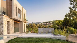 Una casa moderna con fachada de piedra, piscina y césped cuidado.
