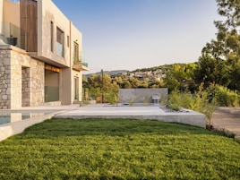 Una casa moderna con fachada de piedra, piscina y césped cuidado.