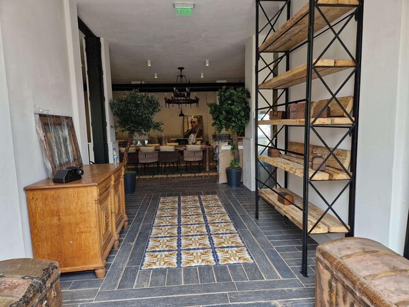 A modern interior with a tiled floor, wooden furniture, and a black metal shelving unit.