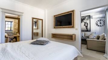 A bedroom with a large bed, a mirror, a clock, and a sofa in the adjacent living area.