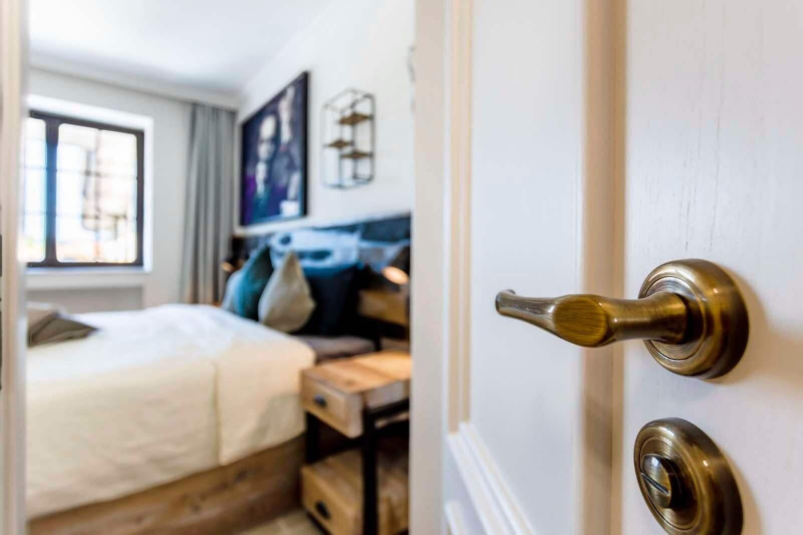 A bedroom with a bed, a desk, and a window.