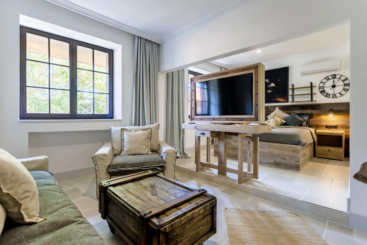 A spacious living area with a large window, a television, a wooden coffee table, and a sofa.