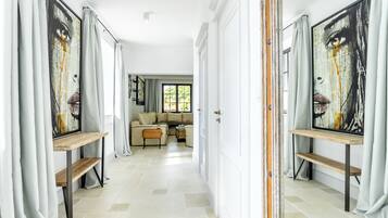 Un pasillo con un conjunto de sofá, un banco de madera y un cuadro en la pared.