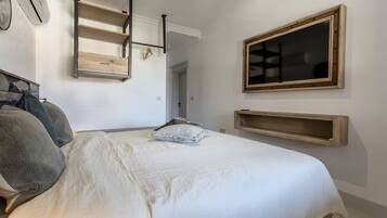 A bedroom with a bed, pillows, a wooden shelf, and a mirror.
