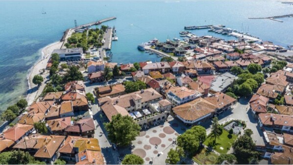 Ett flygbildsfoto av en kuststad med en småbåtshamn, historiska byggnader och ett centralt torg med cirkelformade mönster.