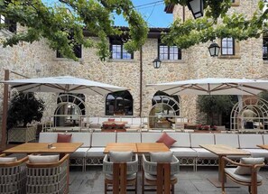 Un espace extérieur aménagé avec des murs en pierre, des meubles blancs et des parasols.