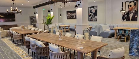 A modern dining area with a wooden table, upholstered chairs, and a chandelier.