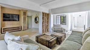 Ein geräumiges Wohnzimmer mit einem großen Flachbildfernseher, einer Holz-Unterhaltungseinheit, einem gemütlichen Sofa und einem Couchtisch.