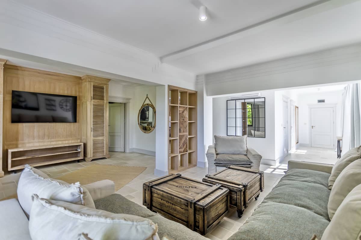 A spacious living room with a large flat-screen TV, a wooden entertainment unit, a cozy sofa, and a coffee table.