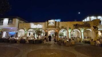 A hotel with a restaurant named 'Tony Gigio' and a sign for 'PINO CHIO' in the background.