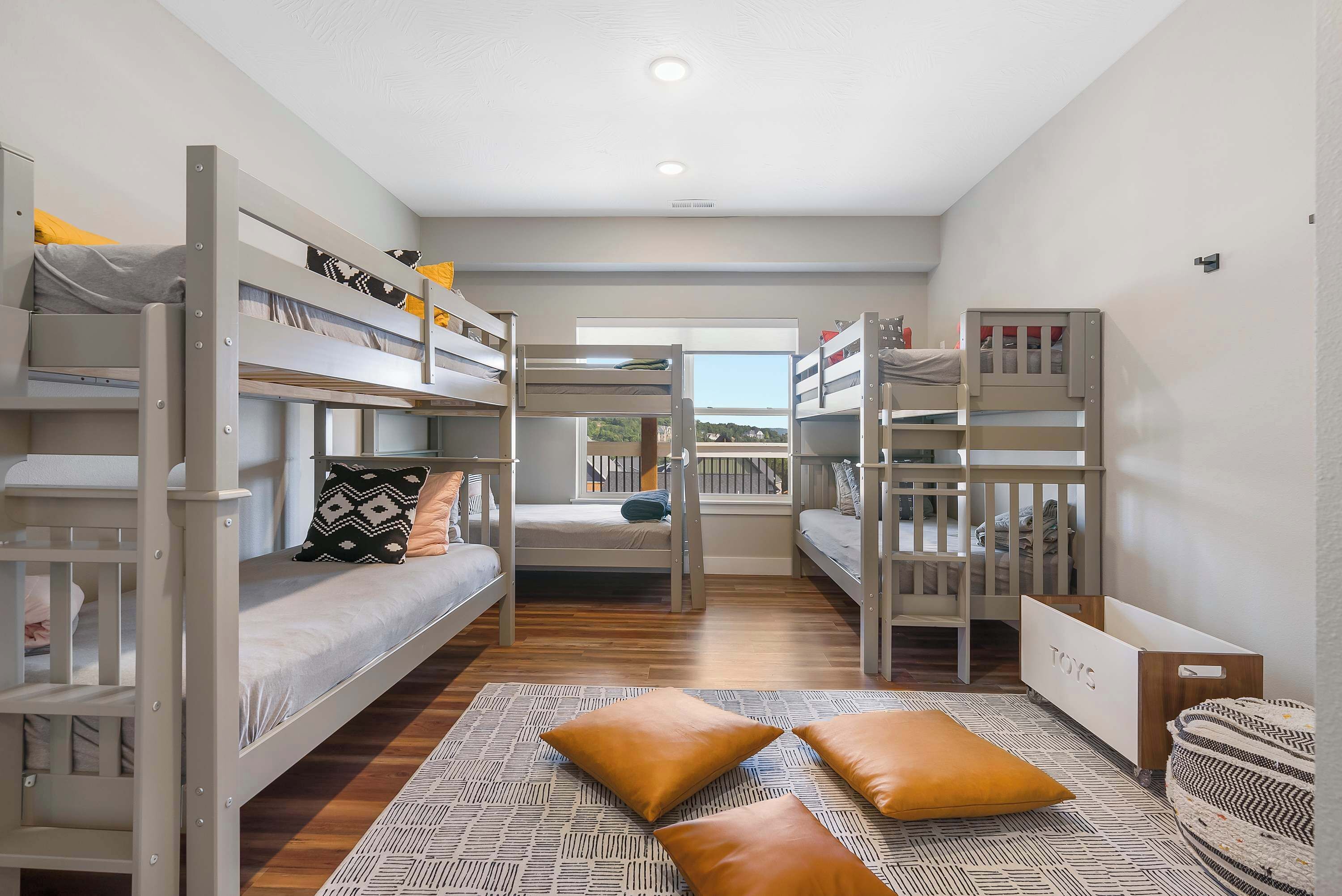 A bunk room with multiple beds, a window with a view, and a patterned rug.