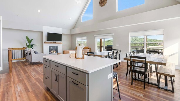 A spacious kitchen with a large island, wooden flooring, and a dining area with a table and chairs. - Ingallview at Branson Cove - Indoor Pool (Hollister)