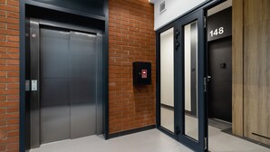 A modern elevator with a digital display, a fire alarm, and a door with the number 148. - Stylish Apartment in Krakow | Balcony and Workspace (Kraków)