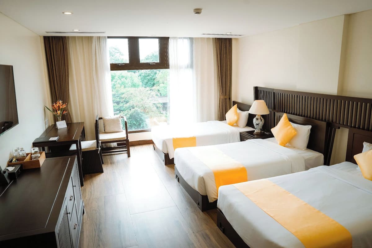 Une chambre d’hôtel avec deux lits, un bureau, une chaise et un téléviseur.