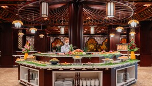 Un buffet disposé de manière à présenter une zone centrale de service, entourée d’éléments décoratifs et agrémenté d’un plafond à motifs.