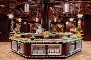 A buffet setup with a central serving area, surrounded by decorative elements and a patterned ceiling. - Tam Chuc Complex (Kim Bang)