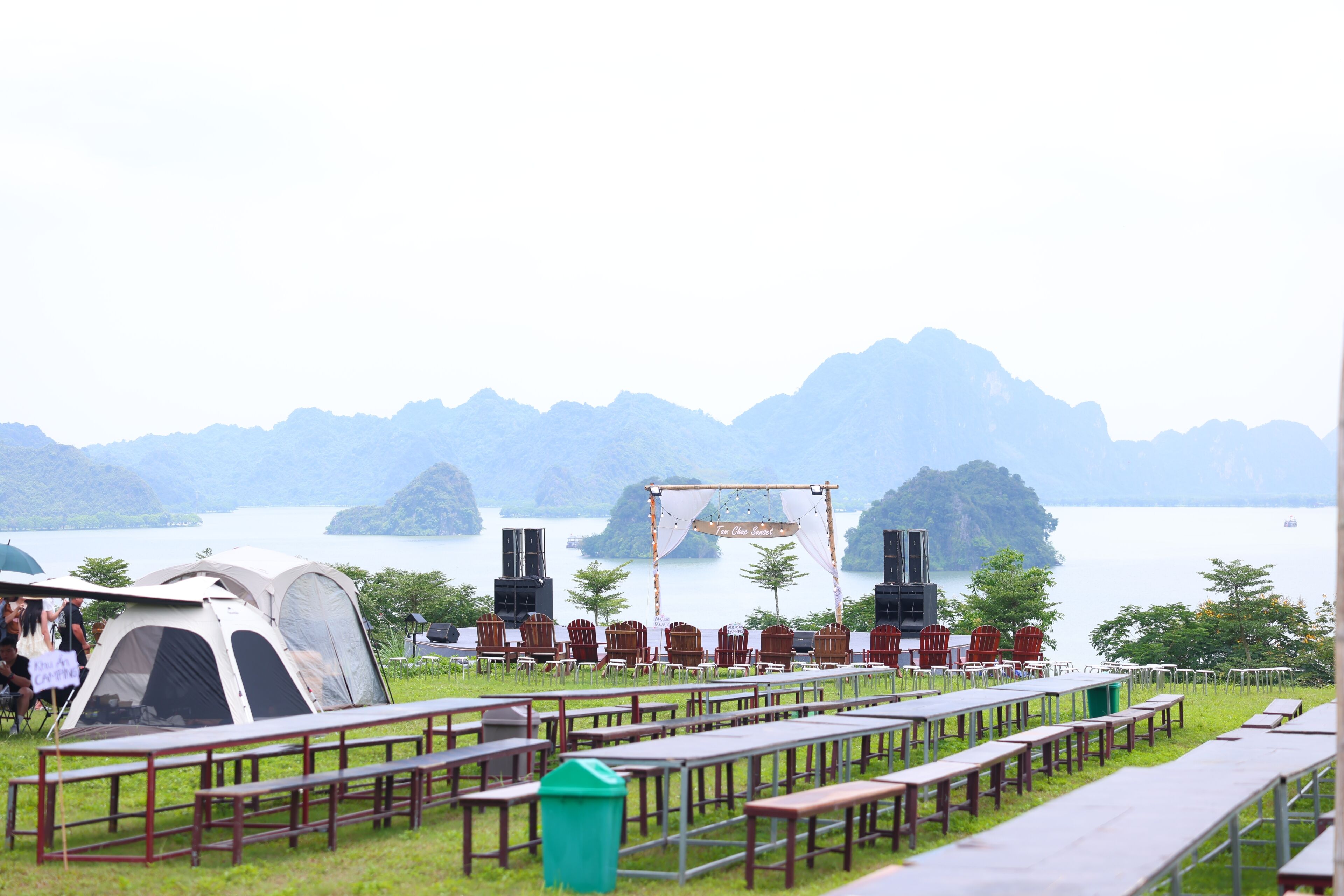 A lakeside venue with tents, tables, and chairs arranged for an event.