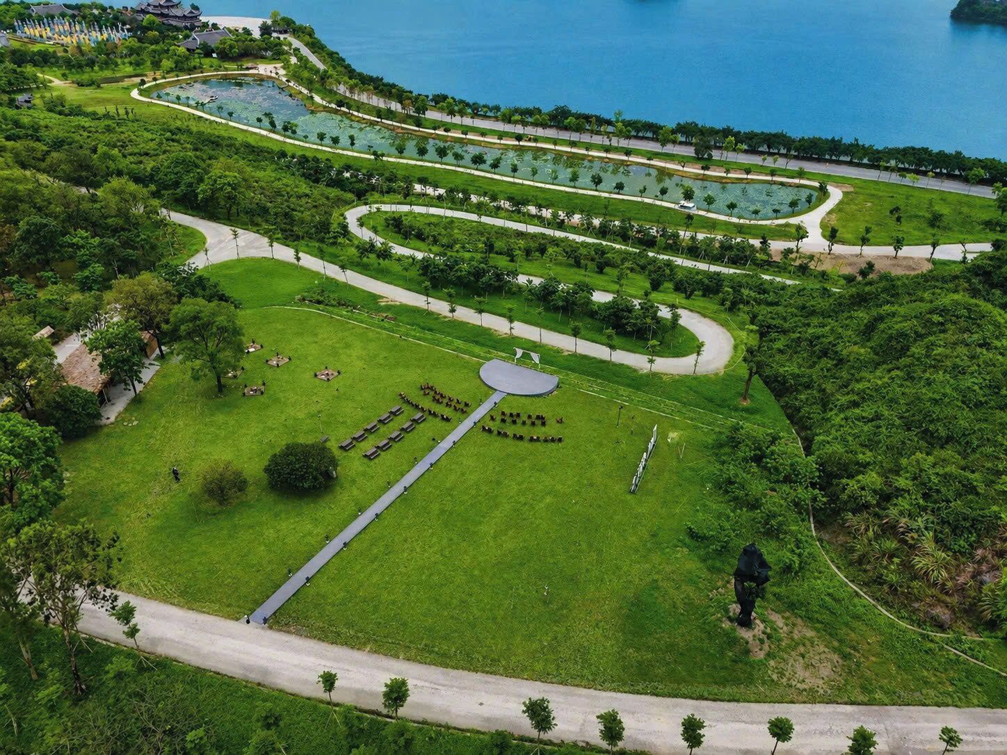 Vista aérea de un parque con senderos, una zona central circular y una masa de agua.