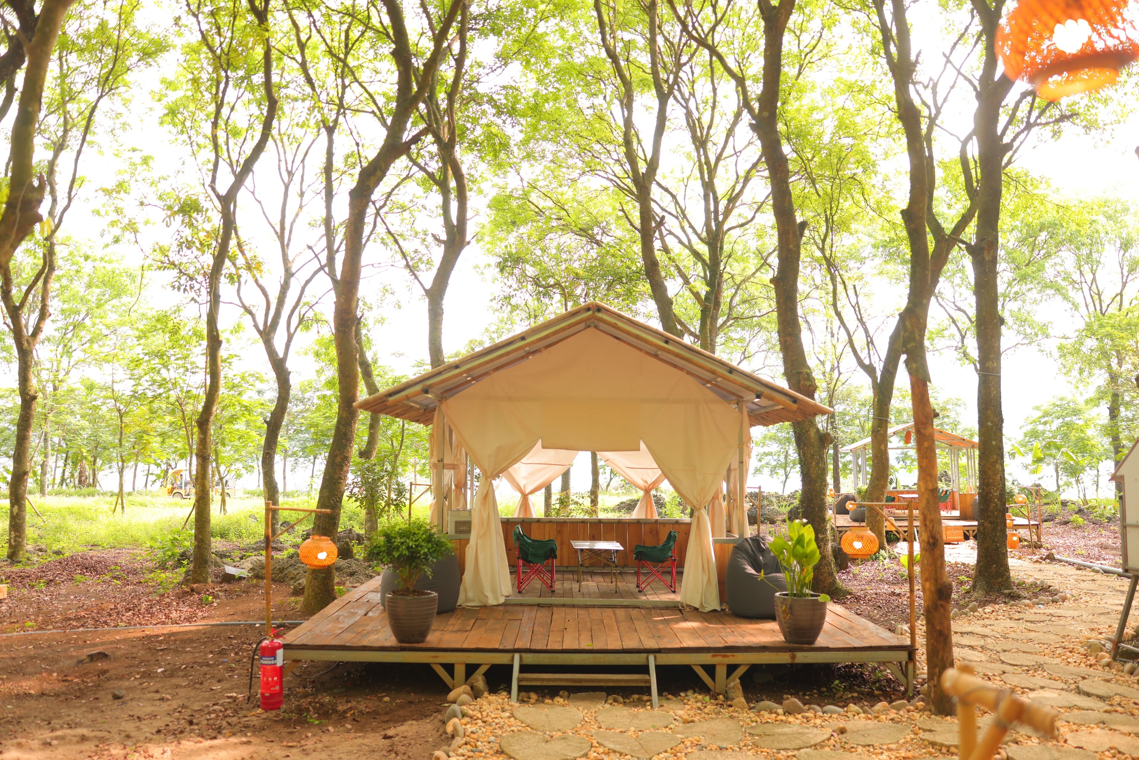 A wooden deck with a covered seating area, surrounded by trees.