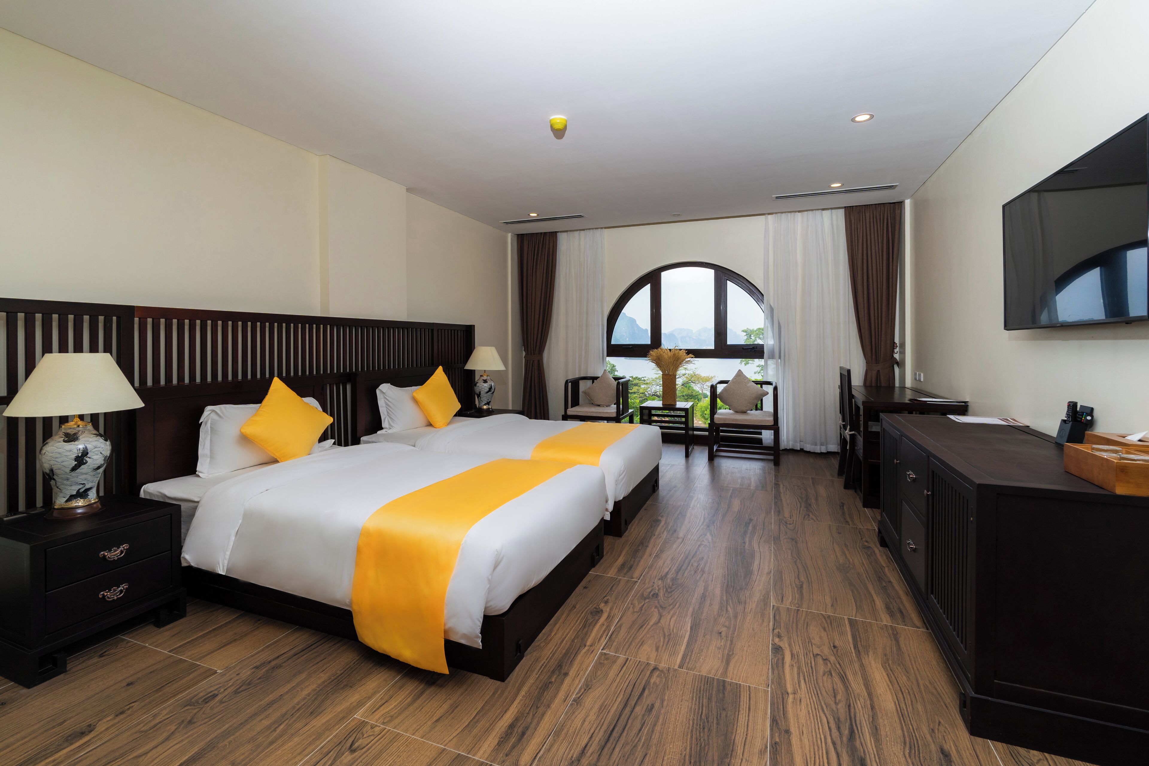 A hotel room with a large bed, a desk, a TV, and a view of the outdoors.