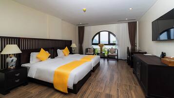 A hotel room with a large bed, a desk, a TV, and a view of the outdoors.