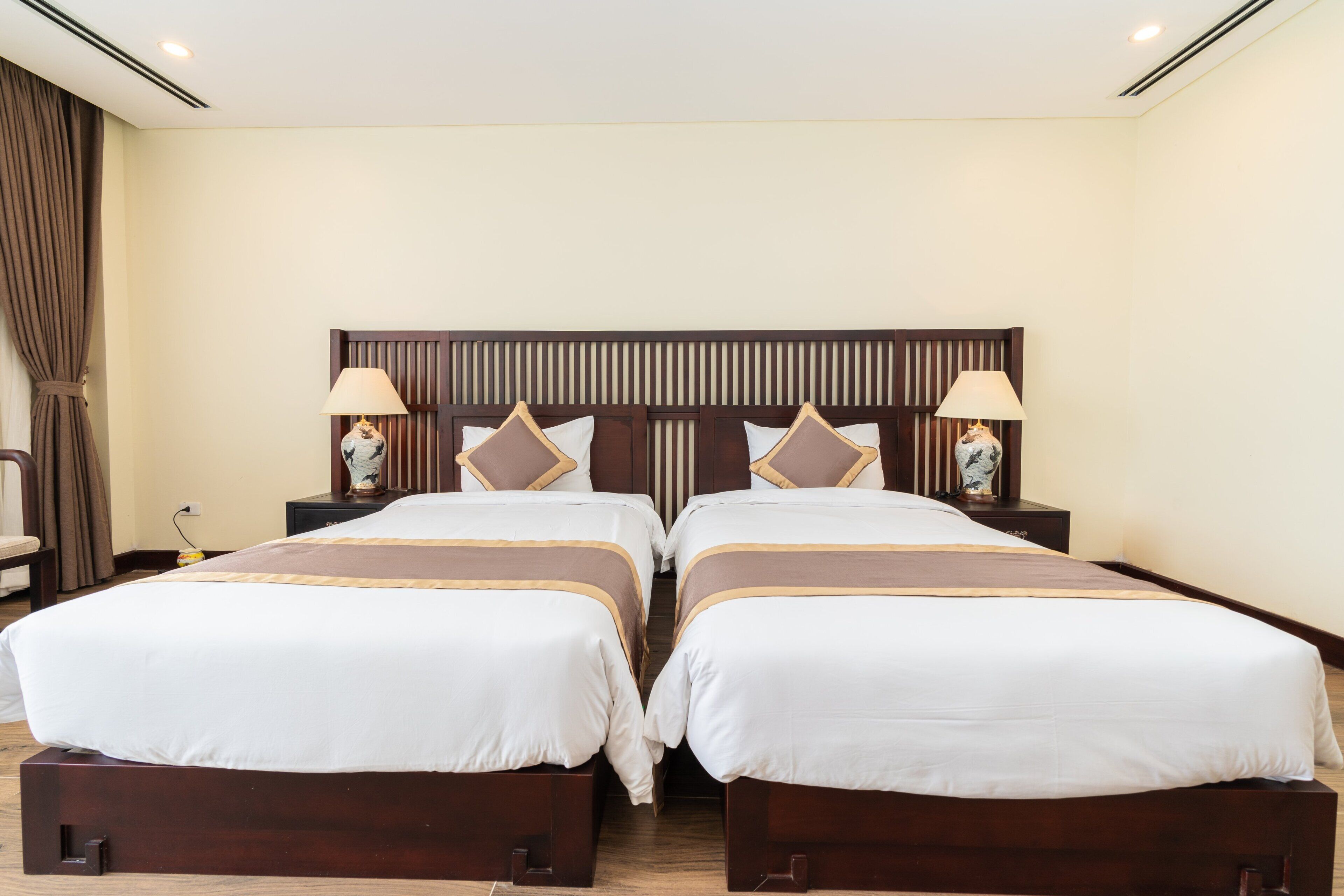 A double bed with a wooden headboard, two bedside tables with lamps, and a curtain on the left.