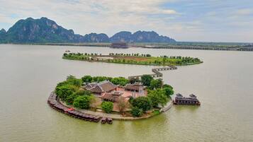 A traditional Chinese pavilion surrounded by a waterway, with a bridge leading to a larger complex.