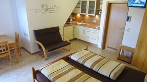 Una habitación compacta con cama, sofá, una pequeña mesa de comedor y kitchenette.