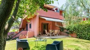 A two-story building with a patio area, outdoor seating, and a staircase leading to the upper floor. - GuestHost - Naxos Seaside Apt with Gardens, Parking and Pool (Giardini Naxos)