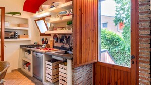 A compact kitchen with a red ceiling, wooden cabinets, and a view through a door. - GuestHost - Naxos Seaside Apt with Gardens, Parking and Pool (Giardini Naxos)