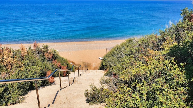 A beach with a staircase leading down to the shore, surrounded by dense foliage. - Phaedrus Living: Amorosa 13 Beachside Villa (Neo Chorio)