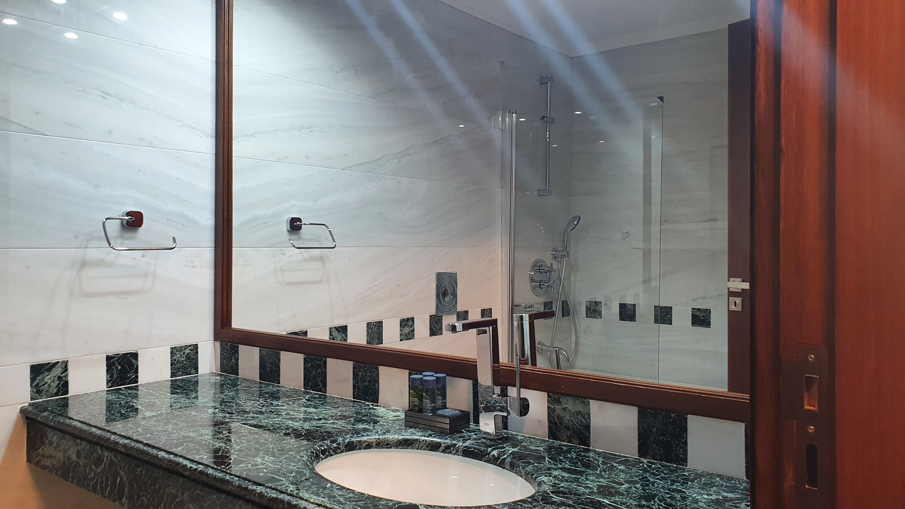A bathroom with a marble sink, a glass shower enclosure, and a large mirror.