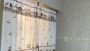 A kitchen with a sink, wooden cabinets, and a window with a patterned curtain. - Hotel Itavera (Puerto Iguazú)