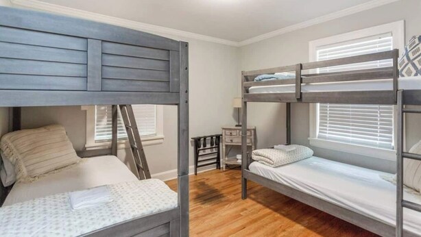 Ein kleines Zimmer mit zwei Etagenbetten, einem kleinen Schreibtisch und einem Fenster mit Jalousien.