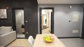 Een moderne woonkamer met een bank, een eettafel met een schaal fruit en uitzicht op de keuken.