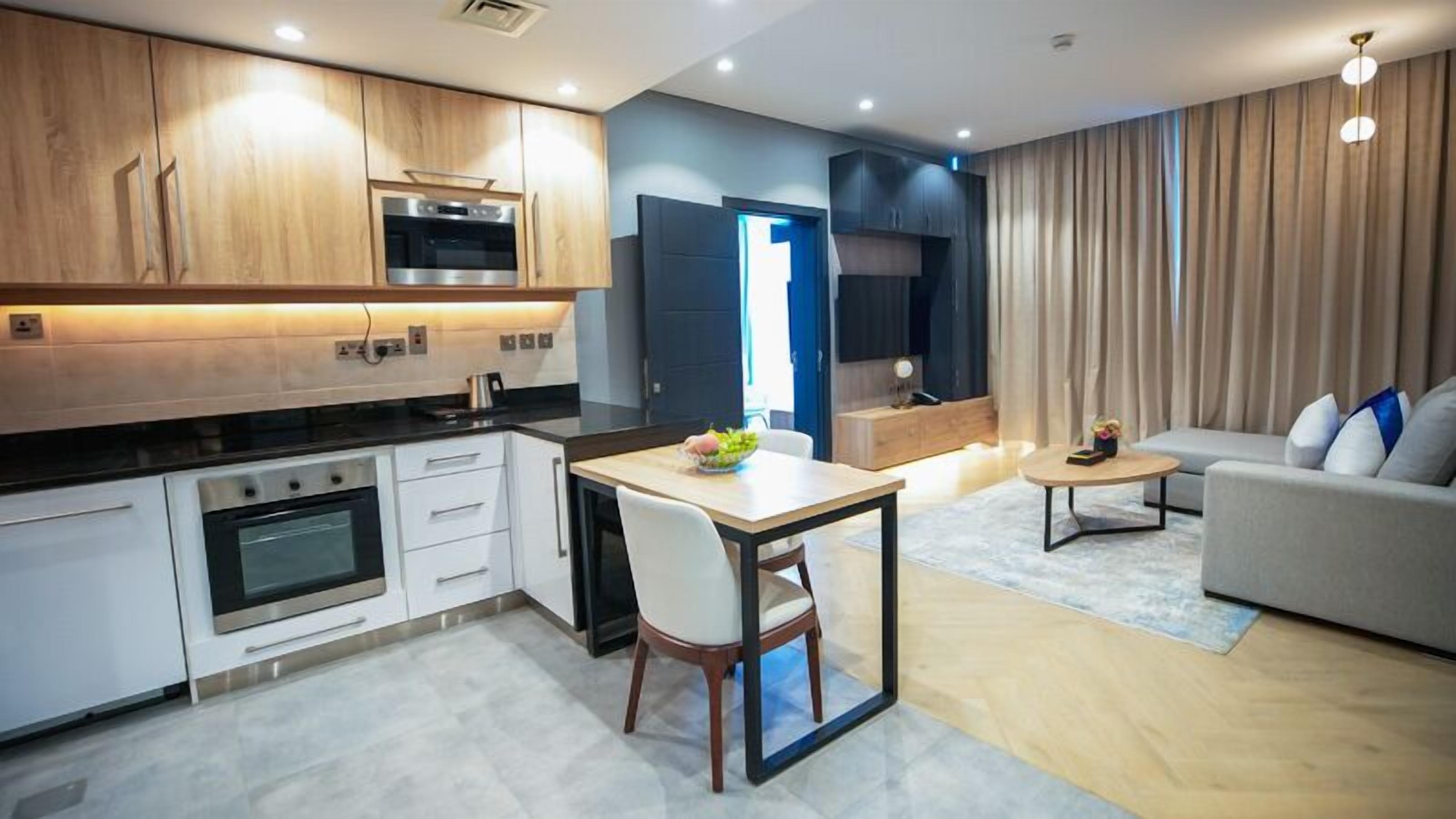 A modern kitchen with white cabinets, a built-in oven, and a dining area with a table and chairs.