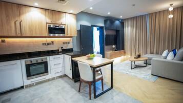 A modern kitchen with white cabinets, a built-in oven, and a dining area with a table and chairs.