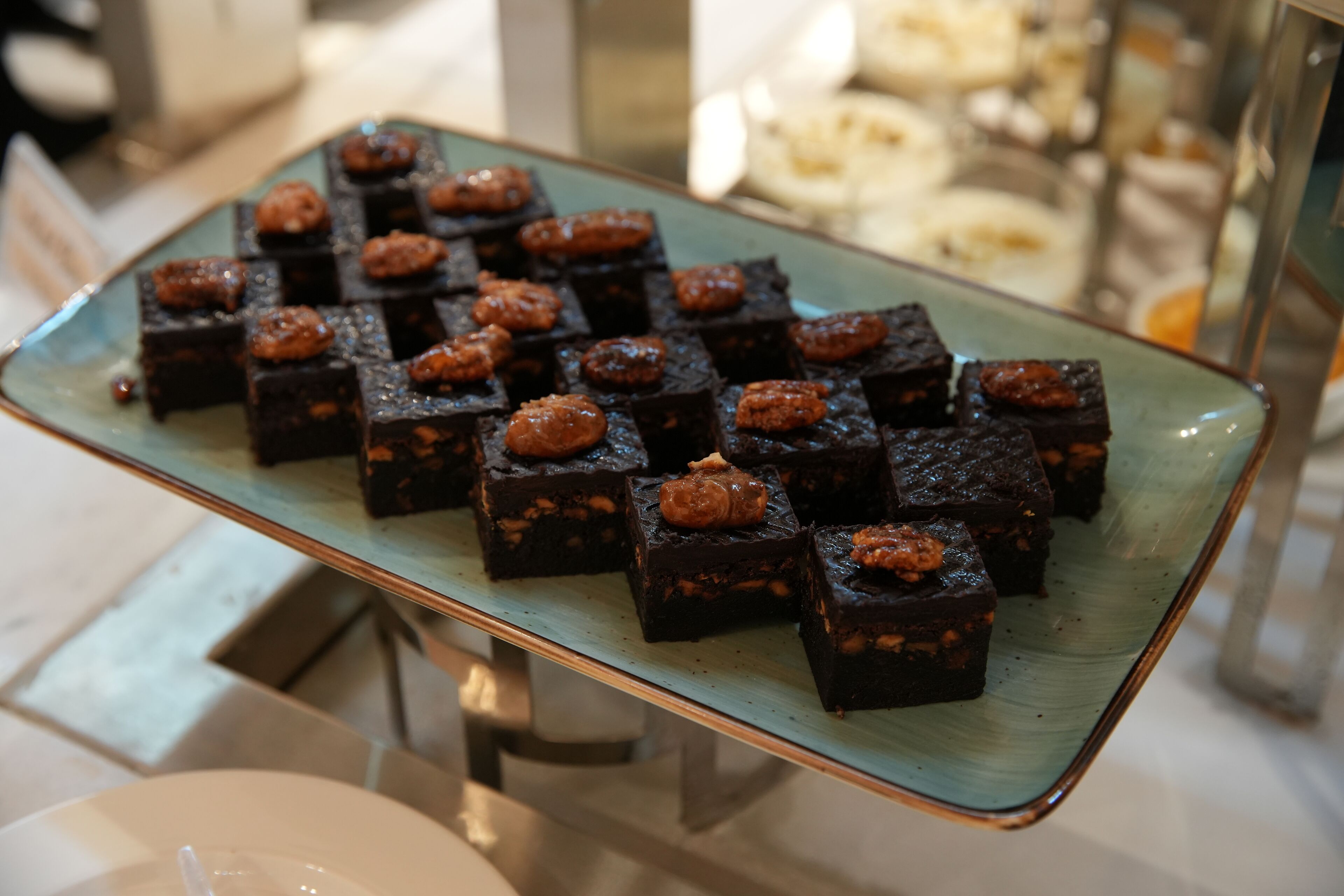 Una bandeja de brownies con nueces sobre una superficie reflectante.