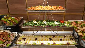 A buffet with various dishes including salads, meats, and a layered dessert.