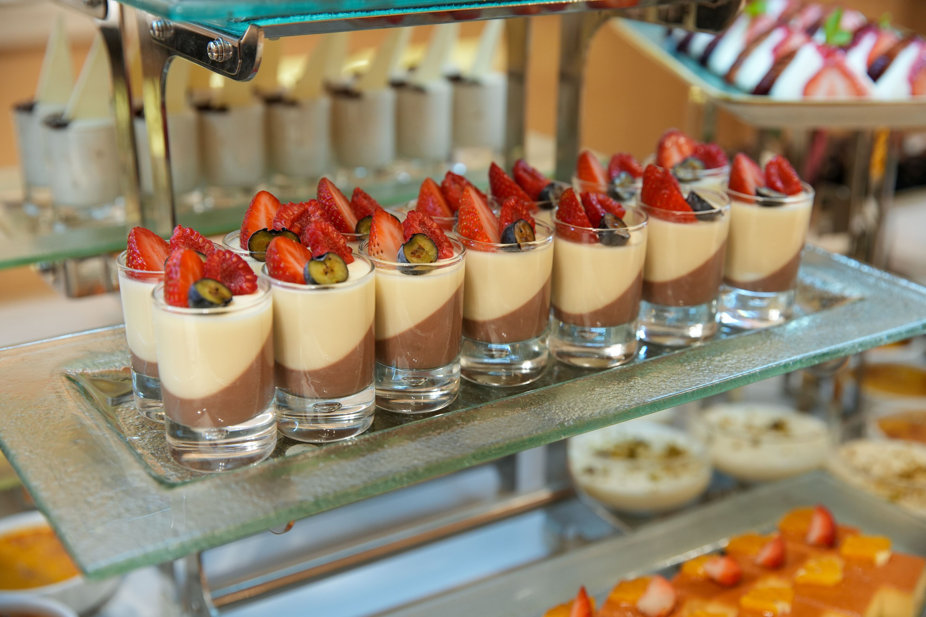 A dessert display with layered chocolate and cream desserts topped with strawberries and kiwi.