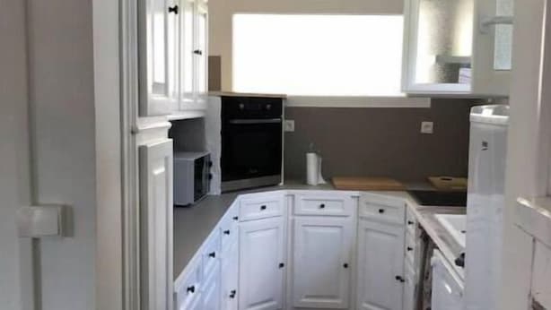 A narrow kitchen with white cabinets, a microwave, and a stove.