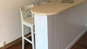 A small kitchenette with a white countertop and a single chair.