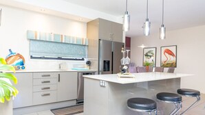 A modern kitchen with a central island, stainless steel appliances, and a bar area with stools.