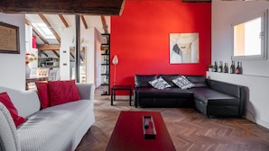 A modern living room with a red accent wall, a black leather sofa, a grey sofa, and a wooden coffee table.