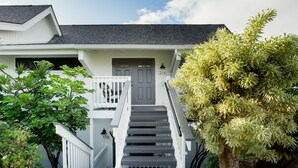 Una casa con una escalera gris que lleva a una puerta principal marcada con el número 216.