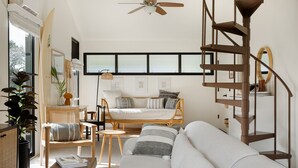 Amplia sala de estar con un sofá, una silla, una mesa de centro y una escalera.